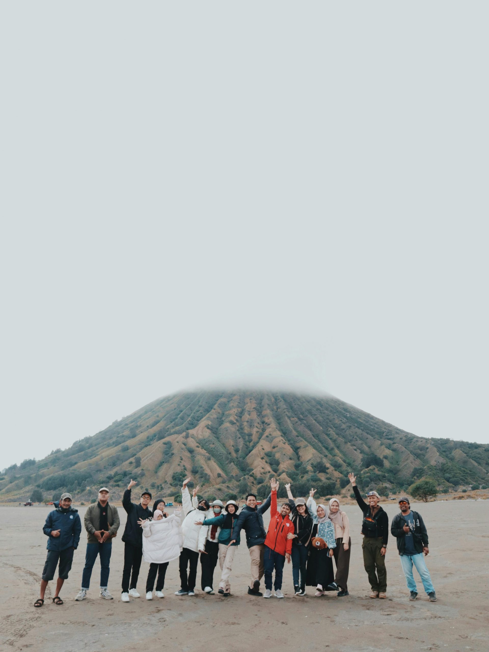 Multicultural group of people celebrating at Mount Bromo with joyful expressions.